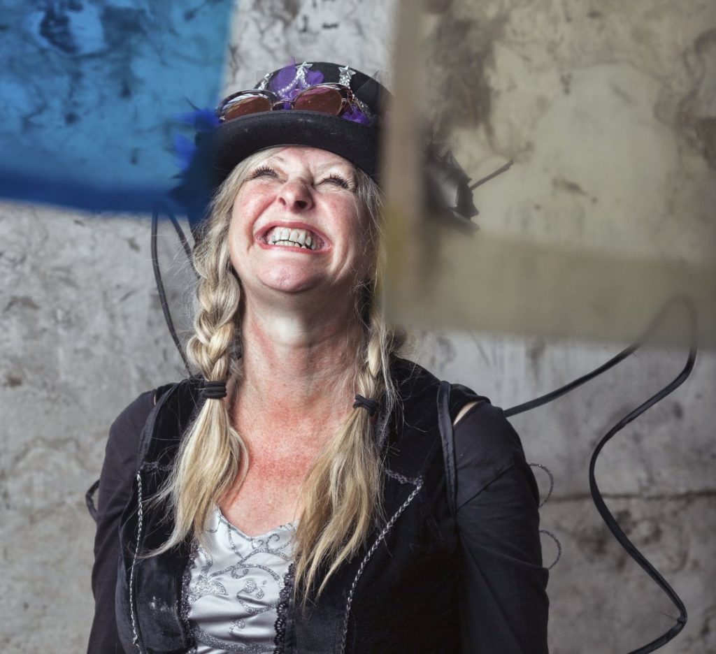 A woman in a cap laughing and looking up at the sky.