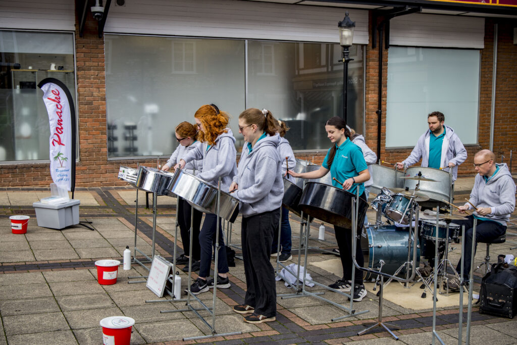 Picture of people playing in a steel band outside.