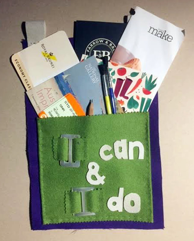 One of the pockets embroidered with lots of little cards, paint brushes , books and arty things sticking out of it - with words on that say I can and I do stitched on